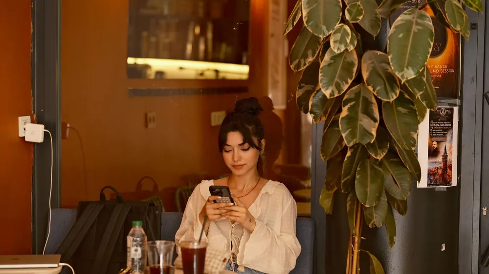 Une cliente consulte son téléphone à la terrasse d'un établissement